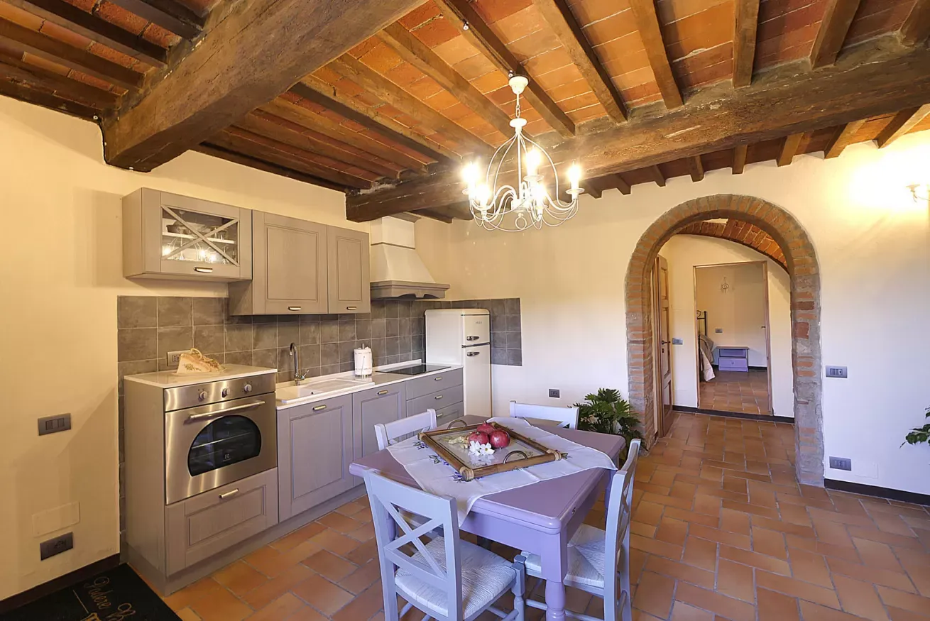 Cucina rustica con soffitto a travi, tavolo da pranzo e arco in mattoni