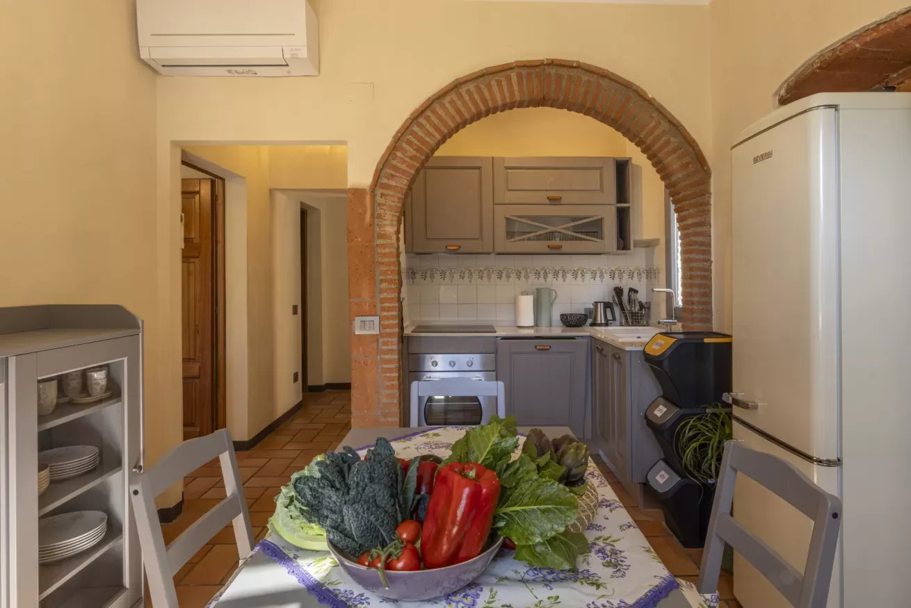 Cucina con tavolo apparecchiato e una ciotola di verdure fresche in primo piano