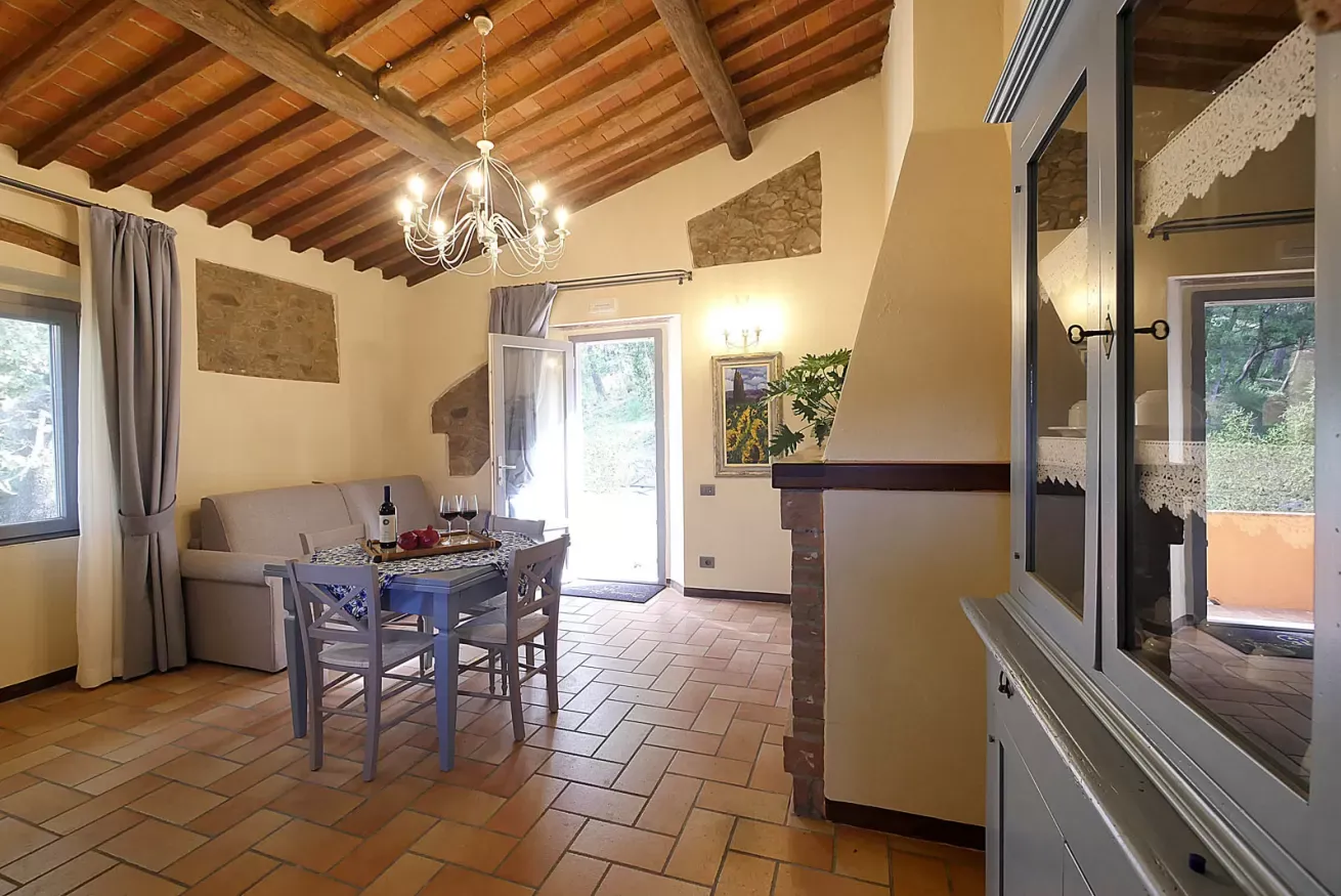Interno rustico con tavolo da pranzo, divano, lampadario e porta aperta sul giardino