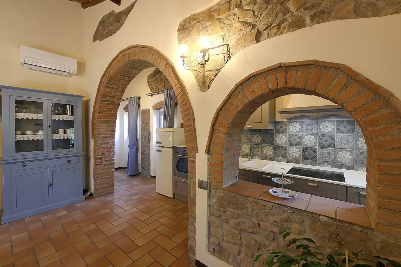 Interno rustico con archi in mattoni, cucina a vista e pavimento in cotto