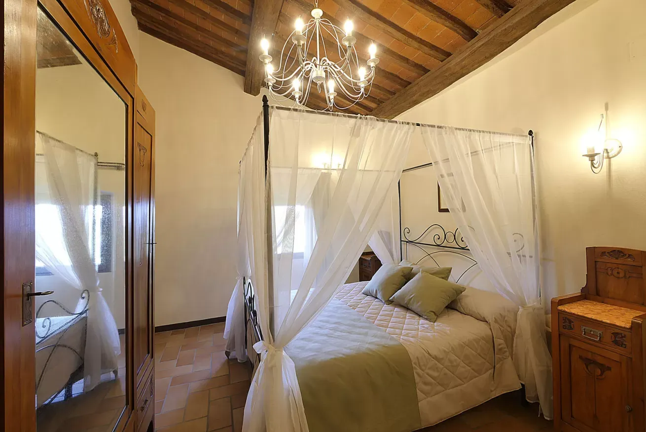 Camera da letto con letto a baldacchino, lampadario e soffitto con travi in legno