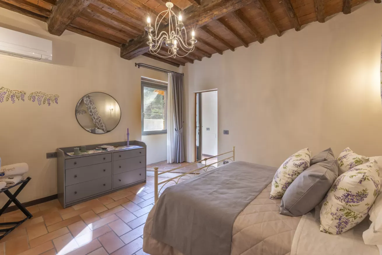 Camera da letto con soffitto in legno, letto matrimoniale, cassettiera e finestra