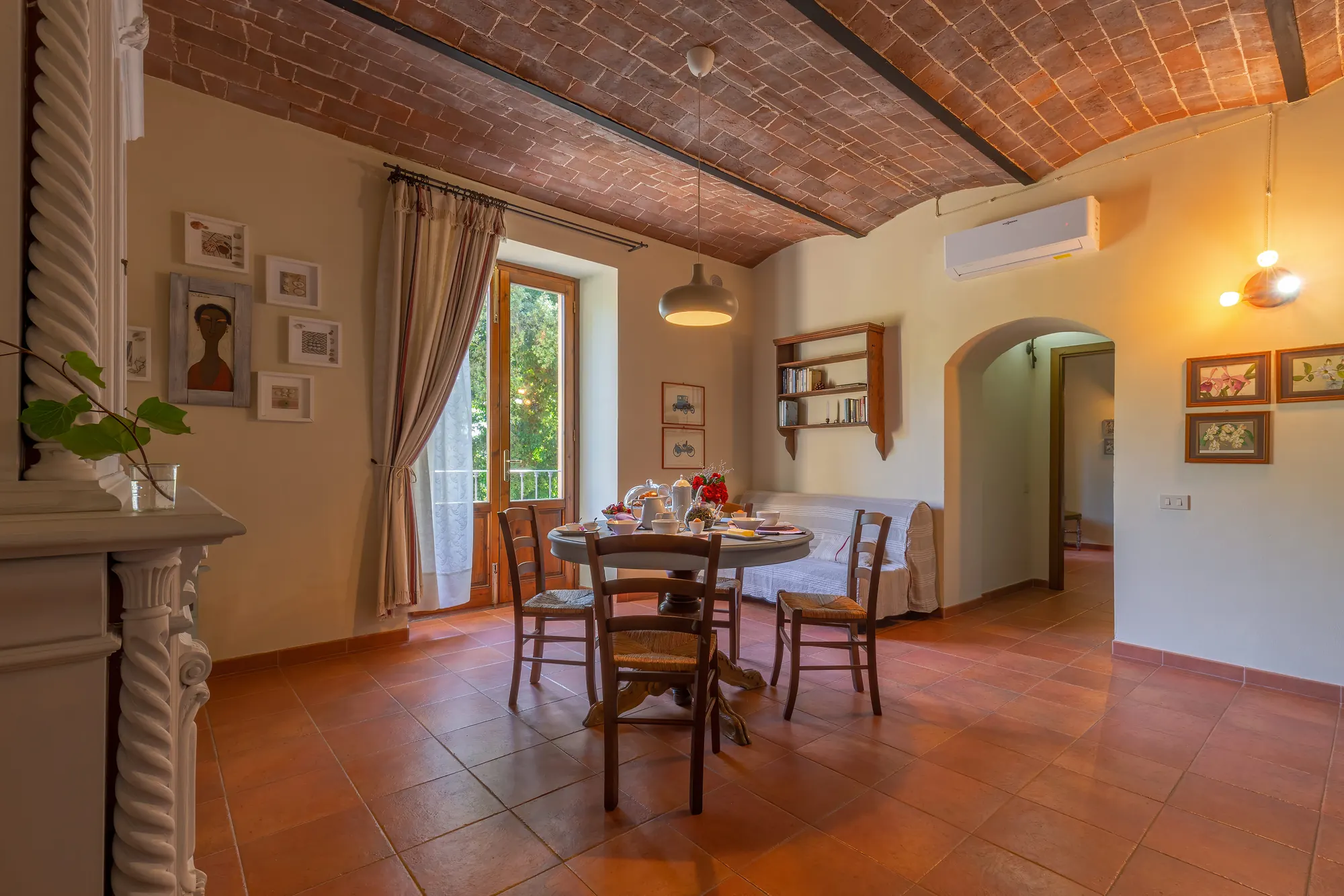 Sala da pranzo accogliente con tavolo apparecchiato, sedie in legno e soffitto a volta in mattoni