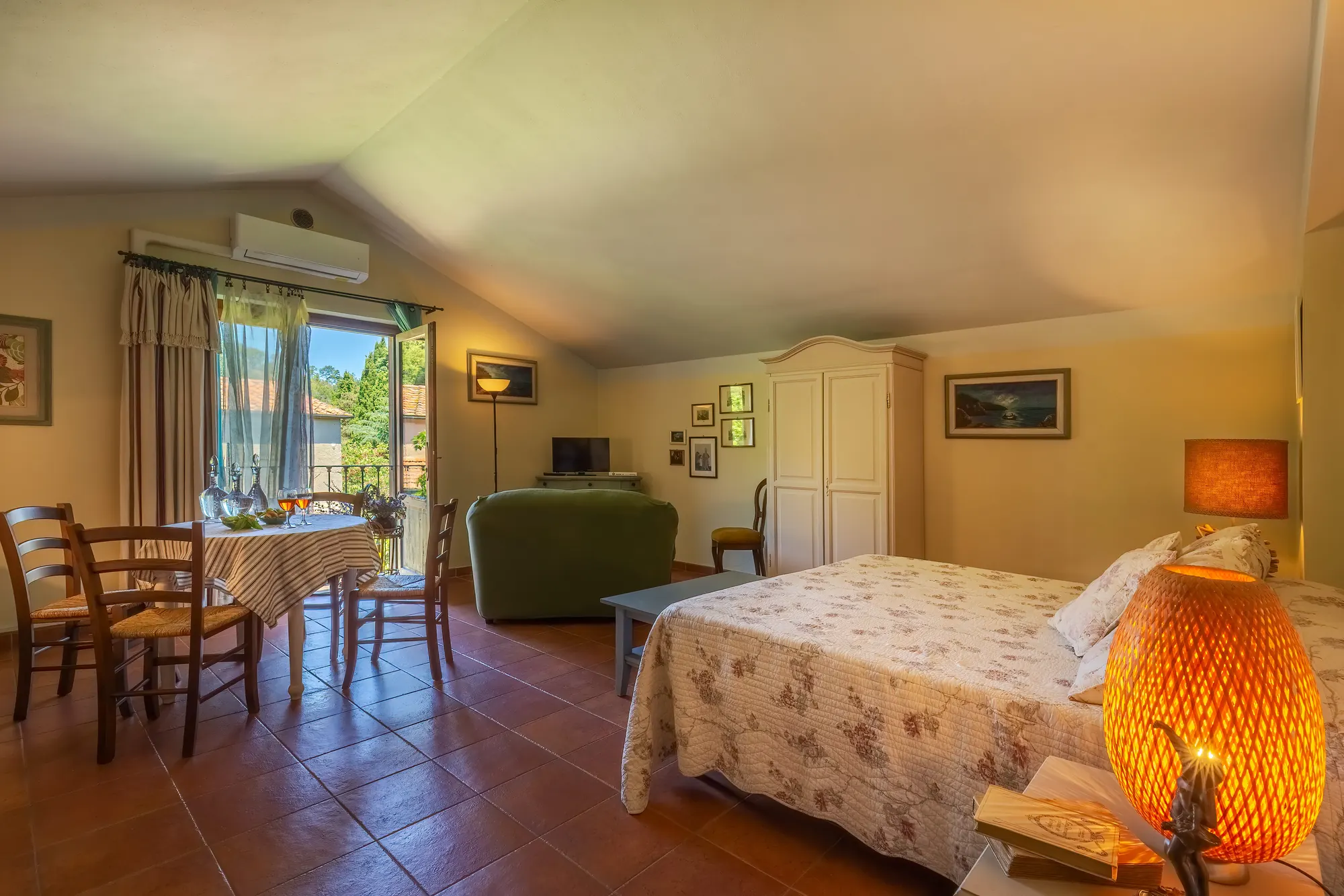 Camera da letto con angolo soggiorno e tavolo vicino alla finestra aperta sul balcone