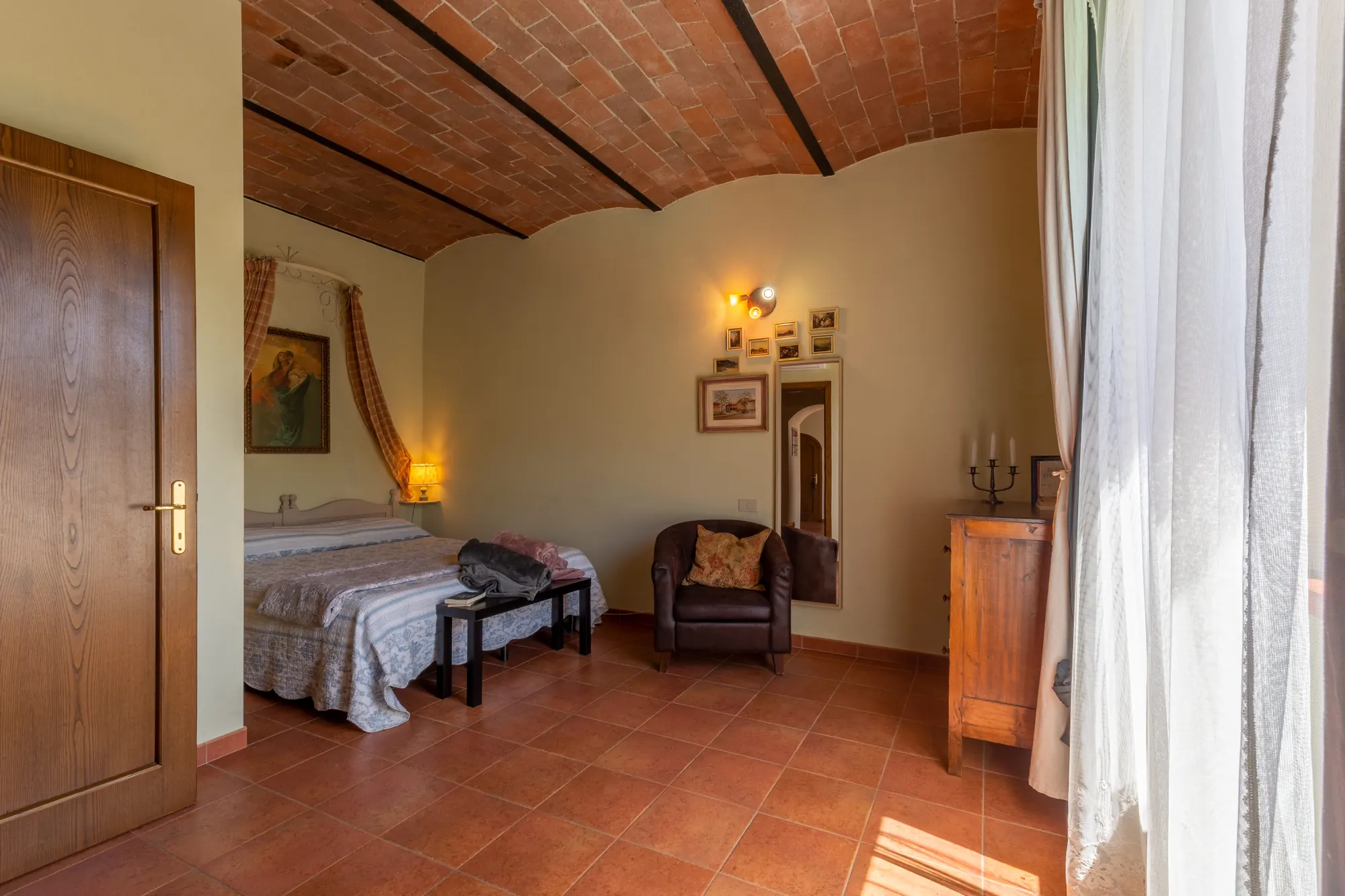 Camera da letto con soffitto in mattoni, letto singolo, poltrona e luce naturale dalla finestra