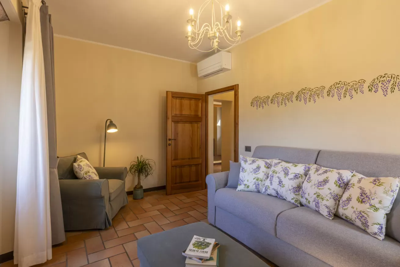 Salotto accogliente con divano, poltrona, lampada da terra e decorazioni floreali alle pareti