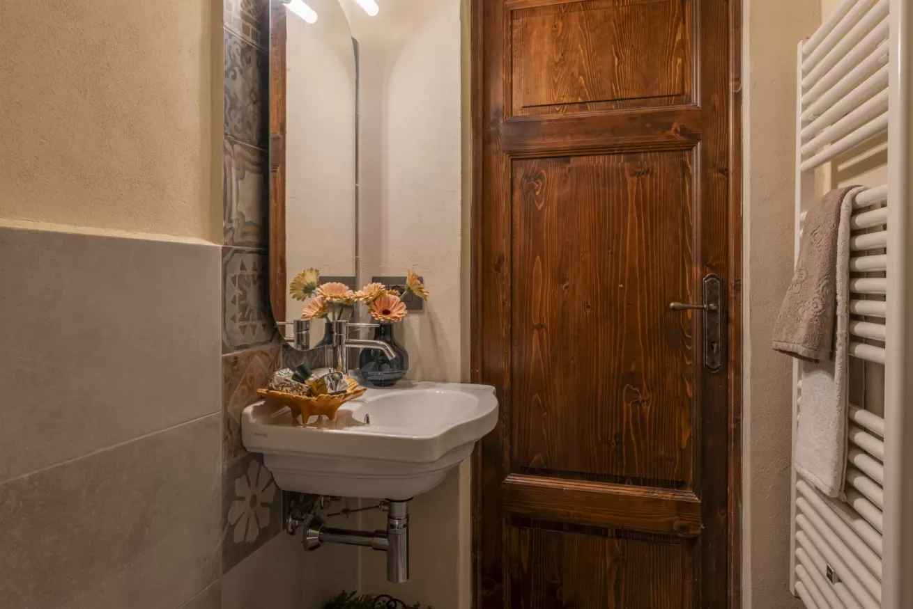 Lavabo da bagno con specchio, porta in legno e termoarredo con asciugamano