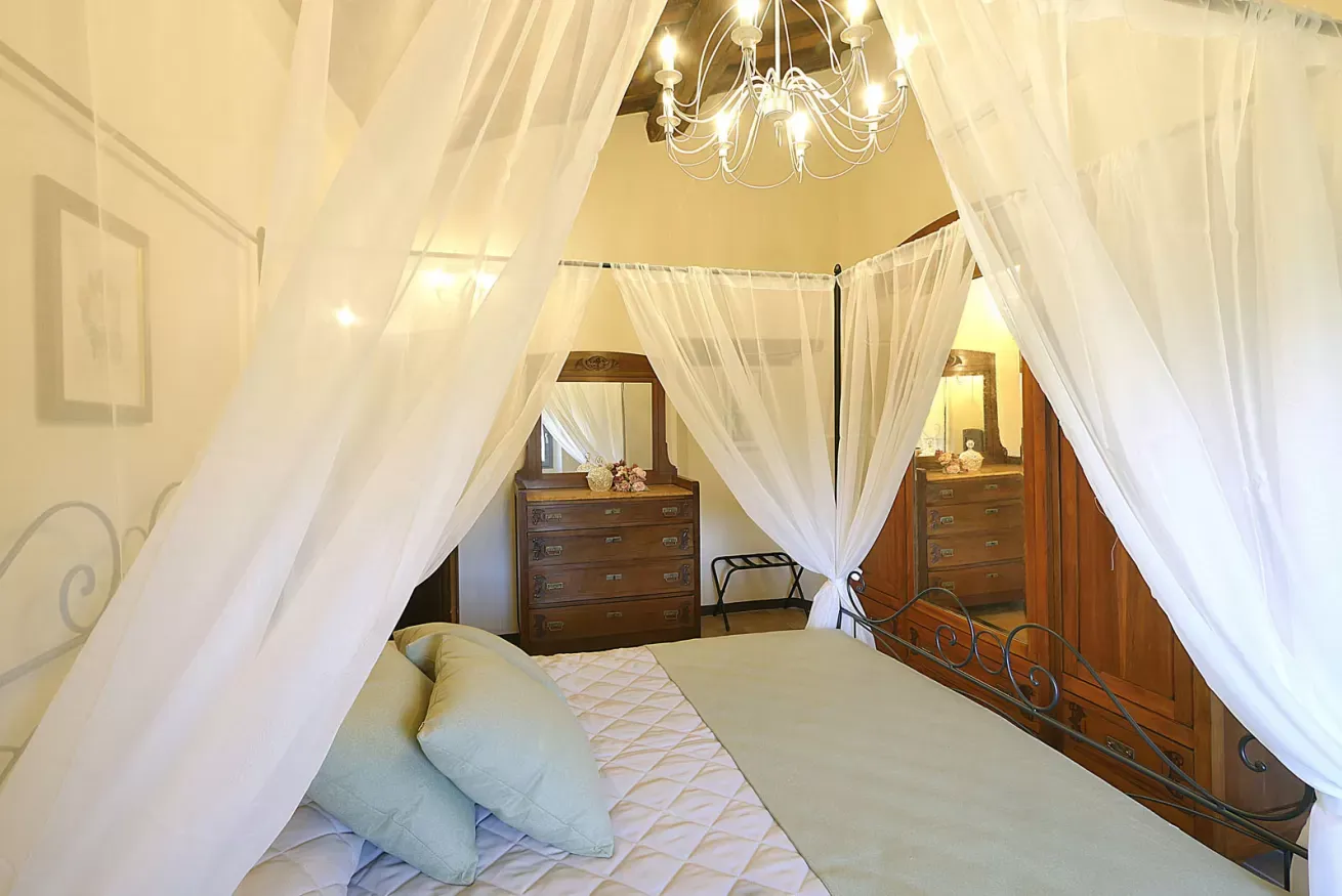 Camera da letto con letto a baldacchino, zanzariera bianca, lampadario e mobili in legno