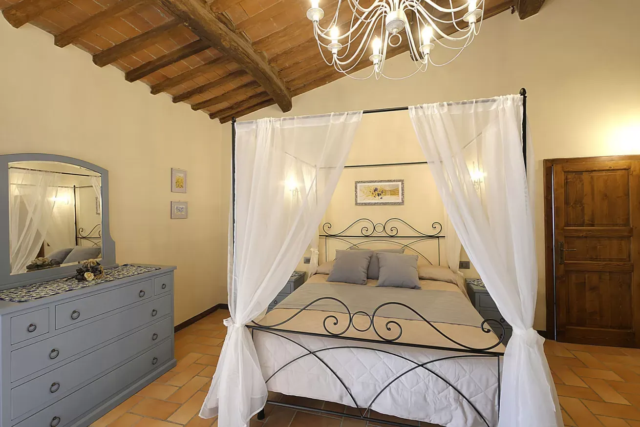 Camera da letto con letto a baldacchino, cassettiera e soffitto con travi in legno