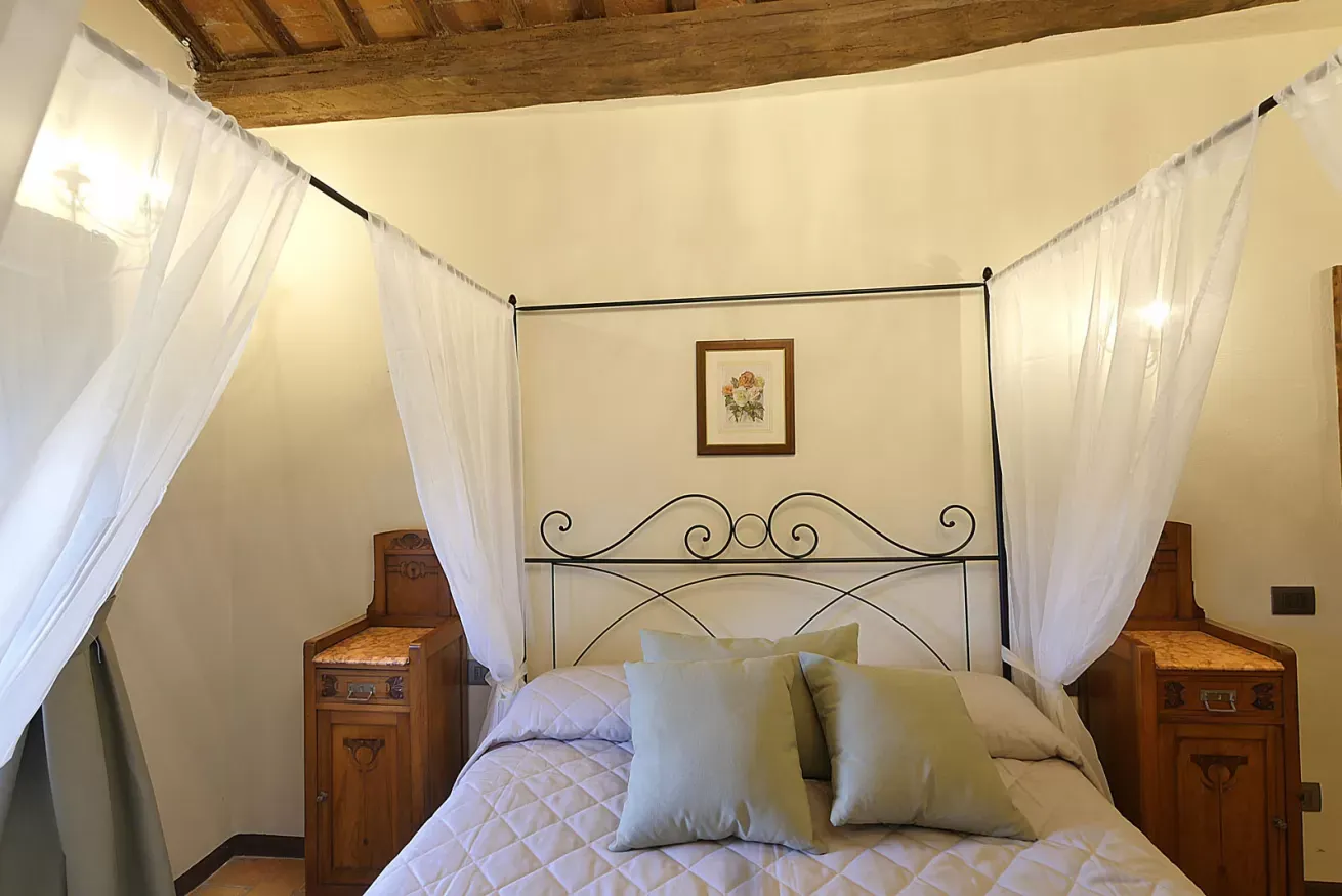 Camera da letto con letto a baldacchino, zanzariere bianche e comodini in legno