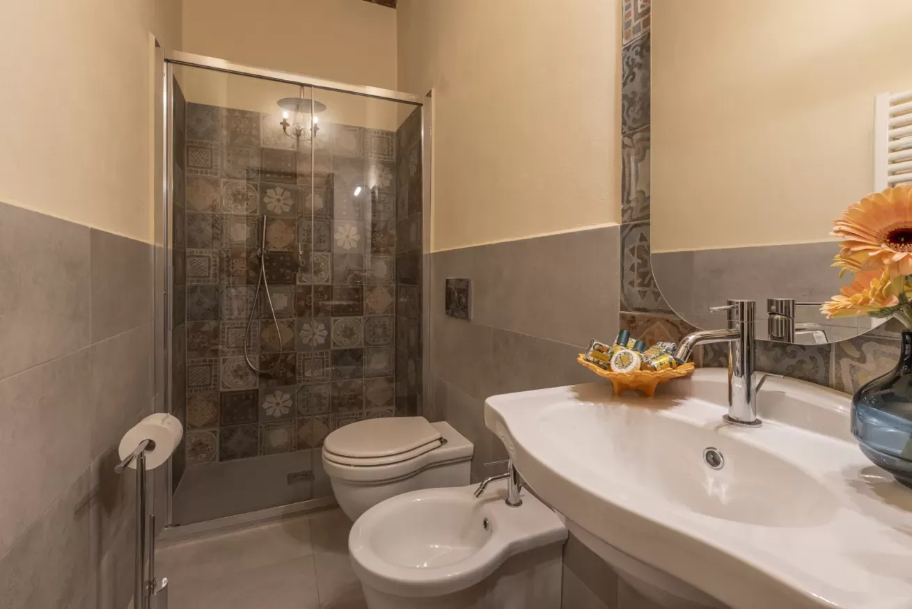 Bagno con doccia in vetro, WC, bidet e lavabo con specchio