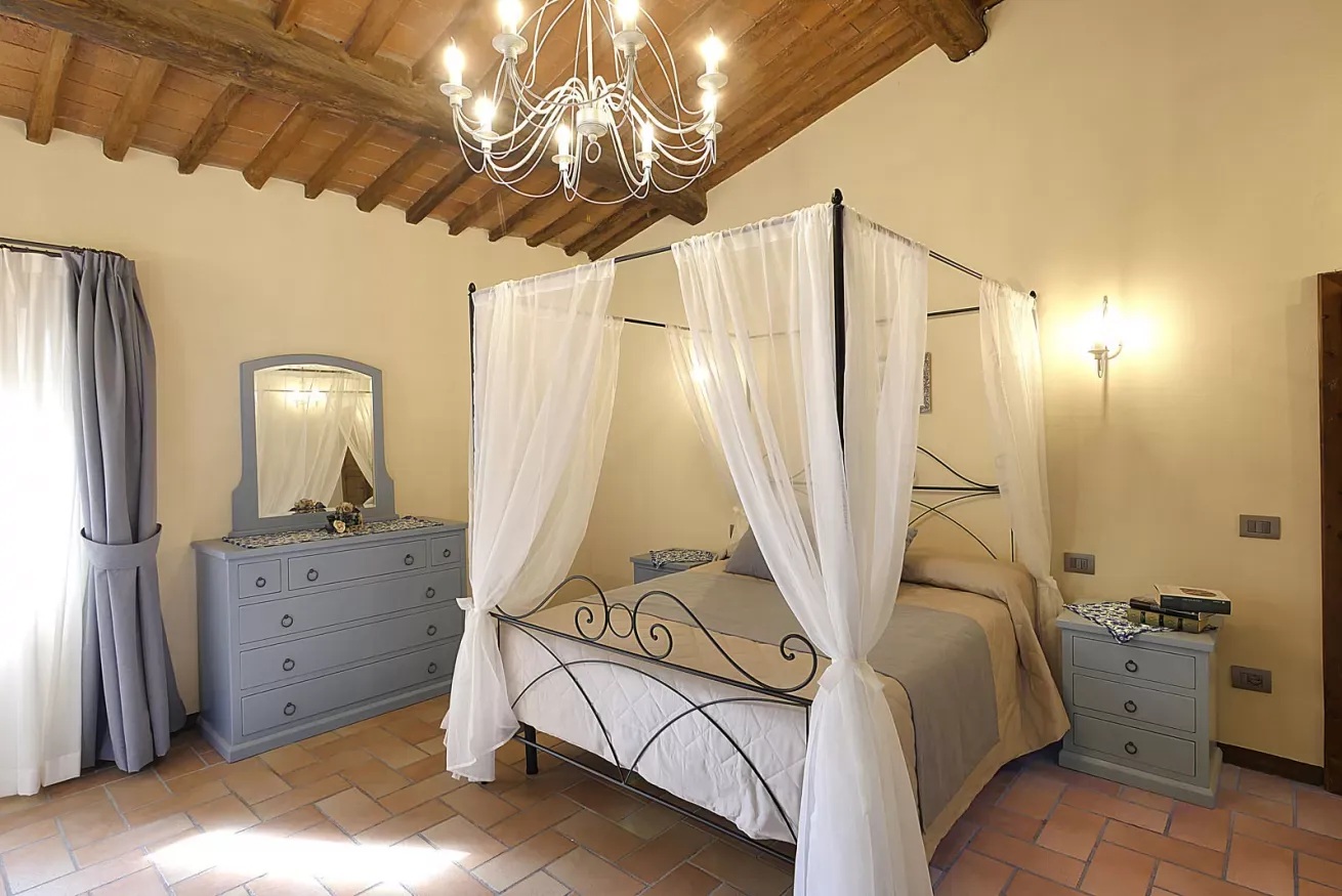 Camera da letto con letto a baldacchino, soffitto in legno e lampadario, arredata in stile rustico-elegante