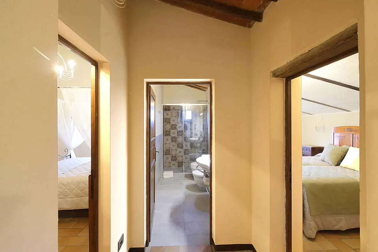 Corridoio con tre porte aperte: bagno al centro e due camere da letto ai lati