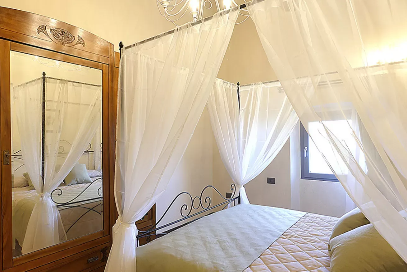 Camera da letto con letto a baldacchino, zanzariera bianca e armadio con specchio