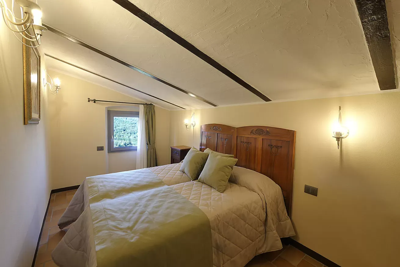 Camera da letto con letto matrimoniale, testiera in legno e finestra con vista sul verde