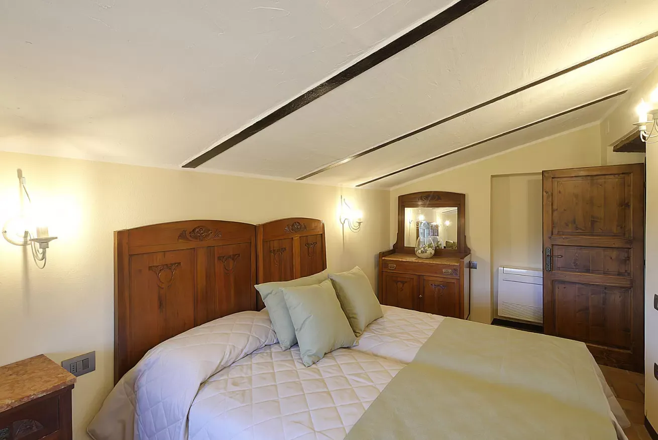 Camera da letto con letto matrimoniale in legno, comodini, cassettiera e porta in legno