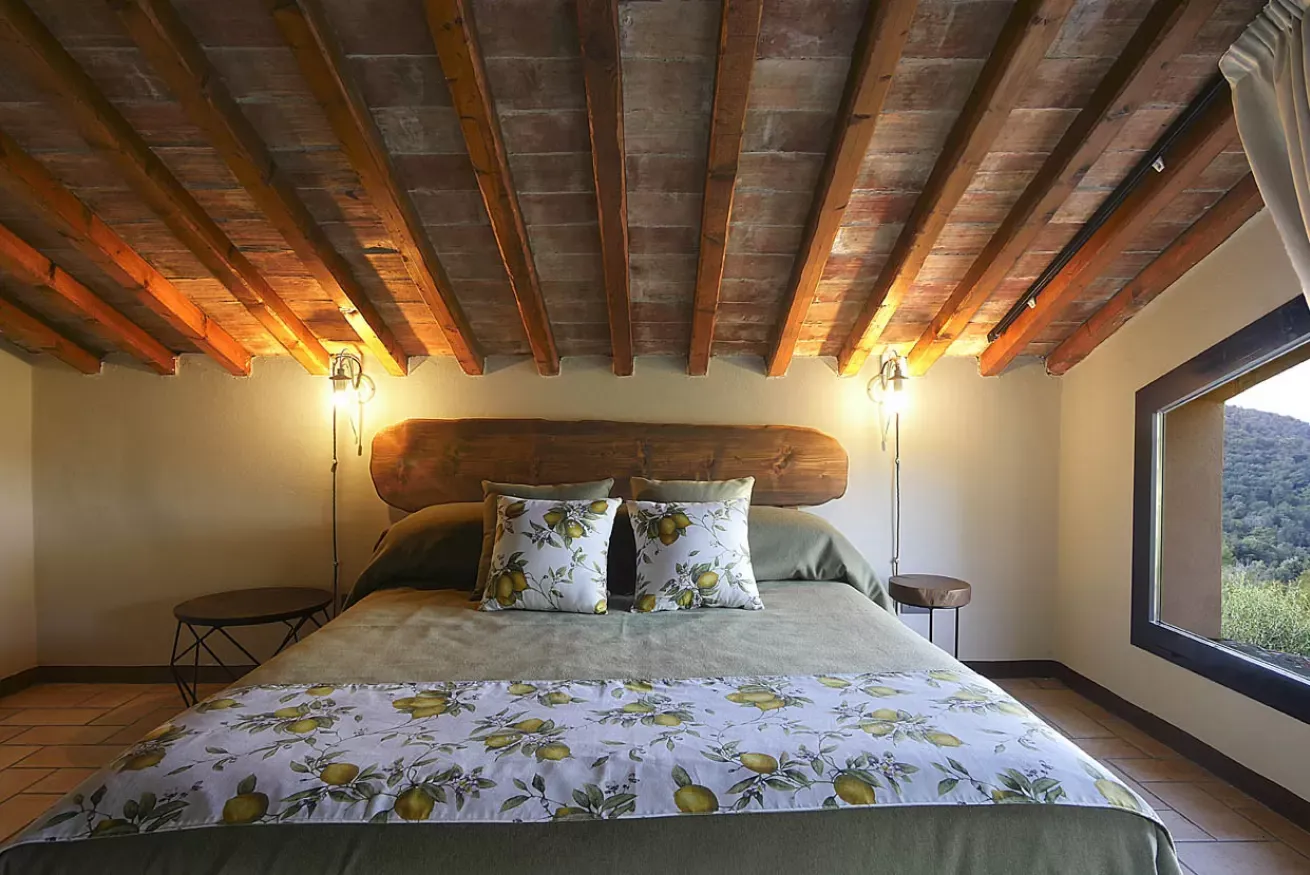 Camera da letto rustica con letto matrimoniale, travi a vista e finestra panoramica