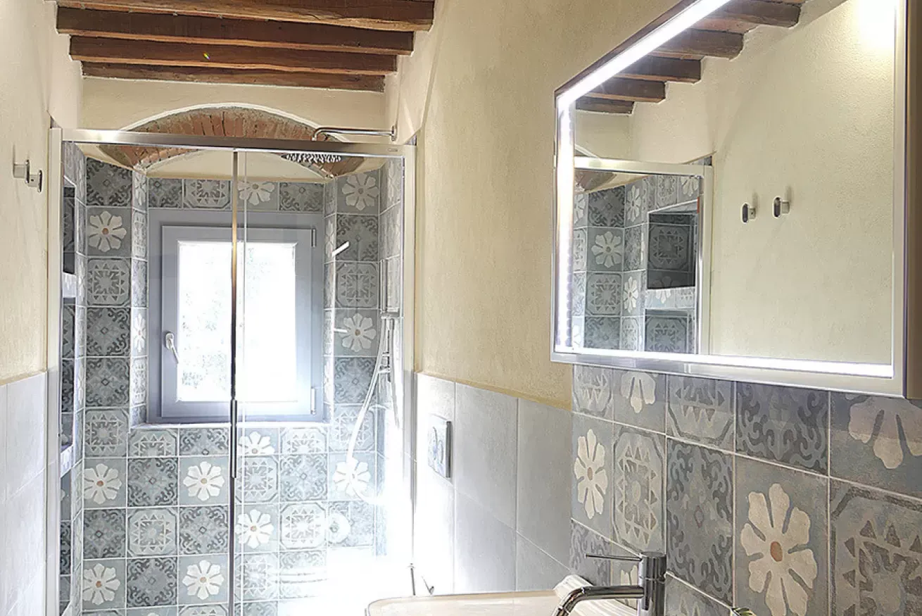 Bagno con doccia in muratura, finestra e specchio illuminato a LED