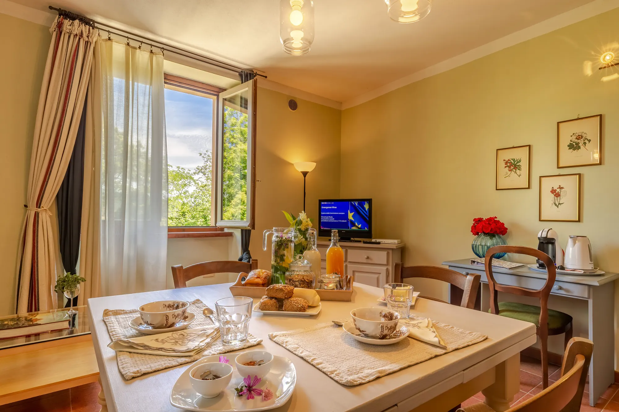 Sala da pranzo con tavola apparecchiata per la colazione e finestra aperta sul verde