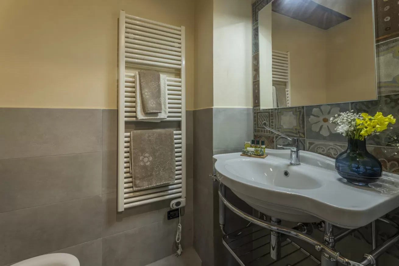 Bagno con lavabo, specchio, scaldasalviette e vaso con fiori