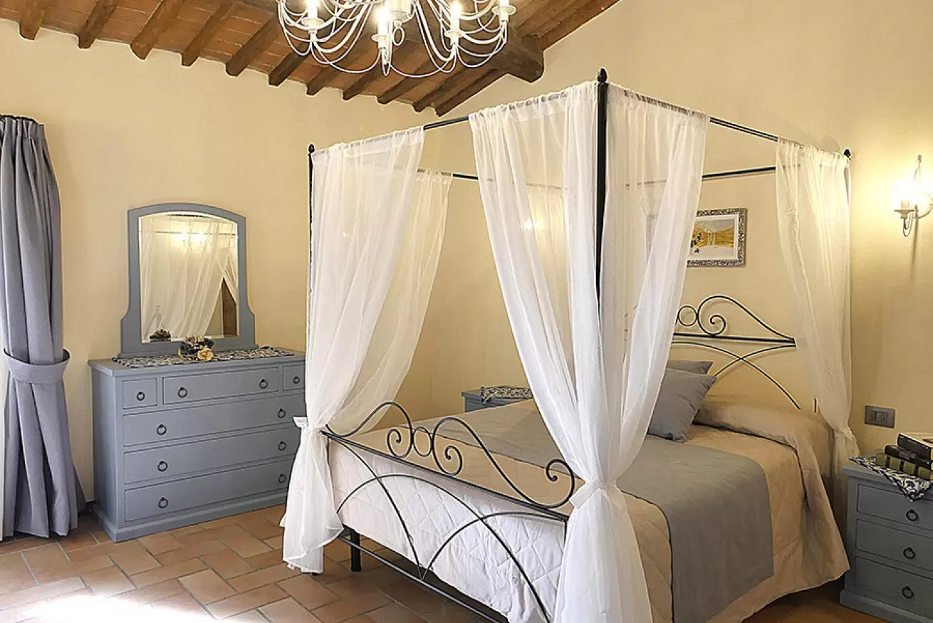 Camera da letto con letto a baldacchino, cassettiera e specchio, soffitto con travi a vista