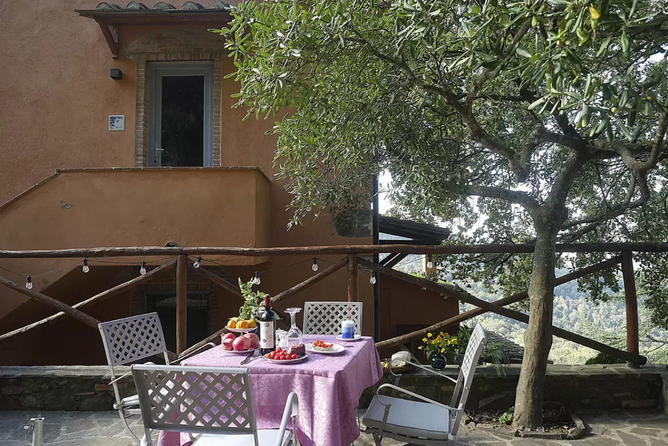 Tavolo apparecchiato all’aperto su una terrazza, con sedie e vista sul paesaggio collinare