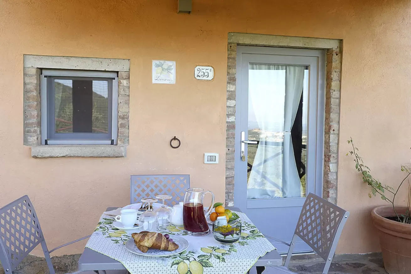 Tavolo apparecchiato per la colazione su una terrazza davanti a una porta e una finestra