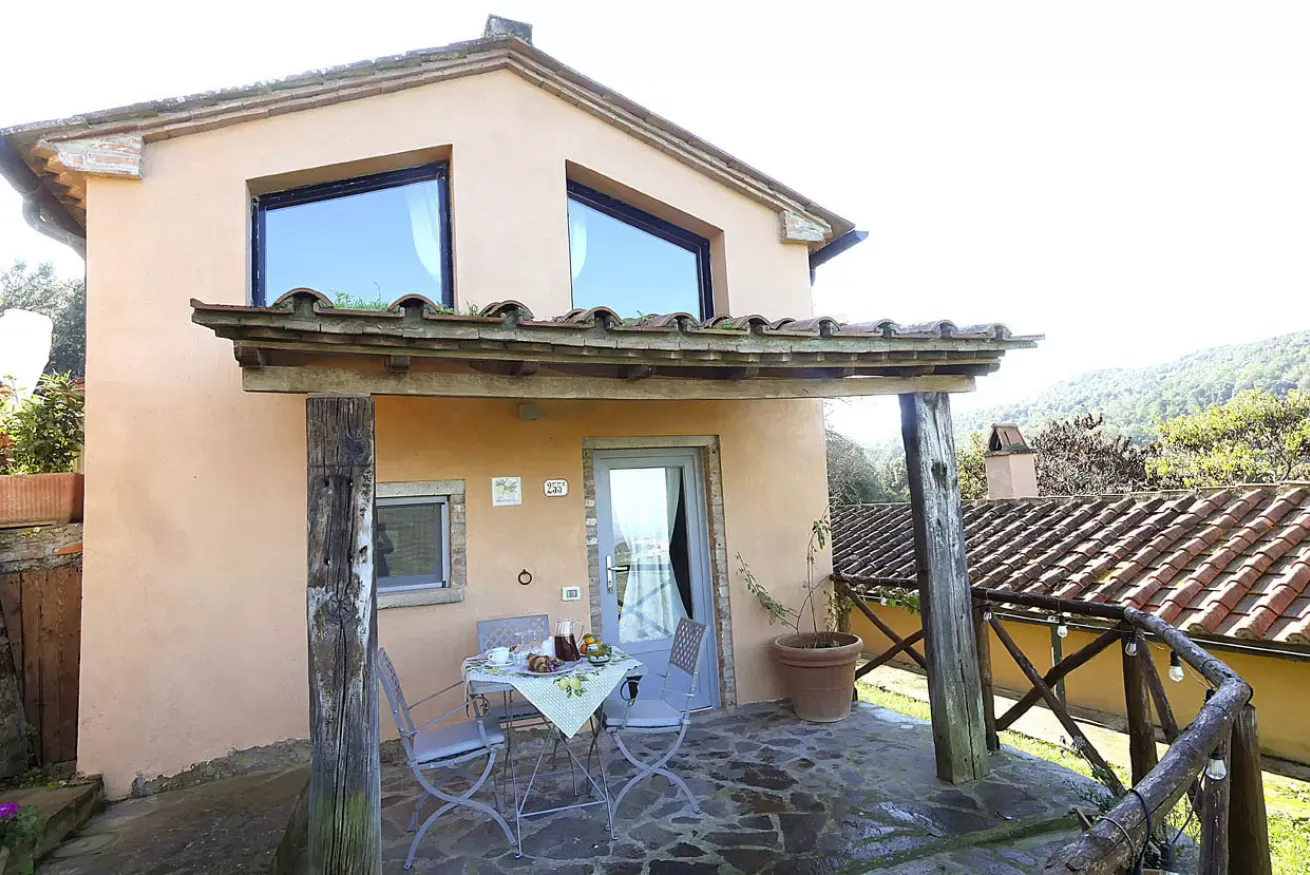 Casa con terrazza coperta, tavolino e sedie all’esterno, con vista sul paesaggio collinare