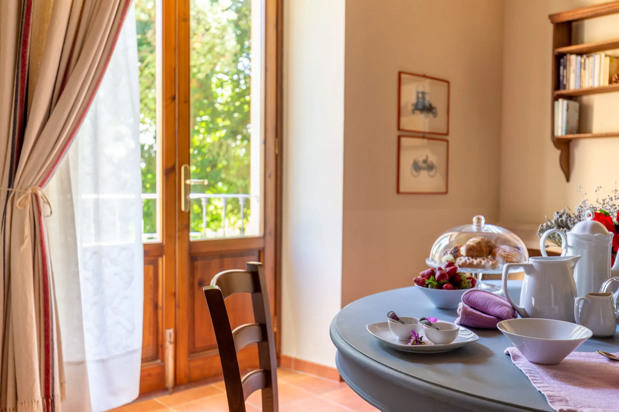 Tavola apparecchiata per la colazione in una stanza luminosa con porta finestra sul giardino