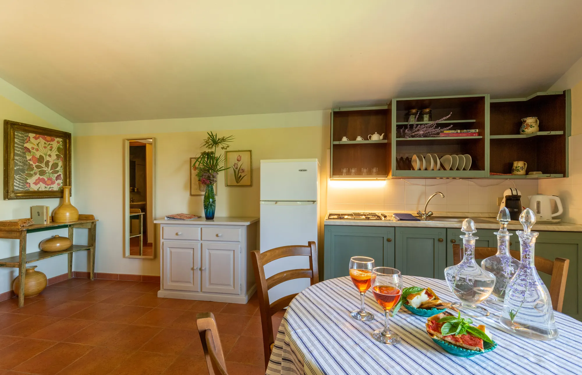 Cucina rustica con tavolo apparecchiato, frigorifero, mobili a muro e decorazioni floreali