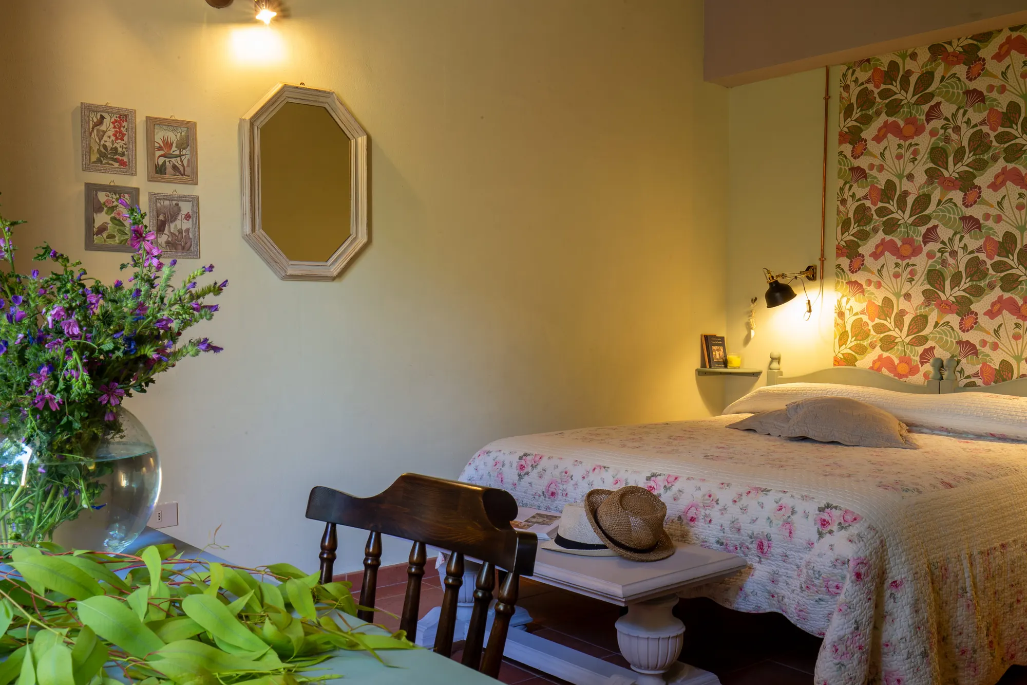 Camera da letto accogliente con letto floreale, specchio a parete, lampade e decorazioni botaniche