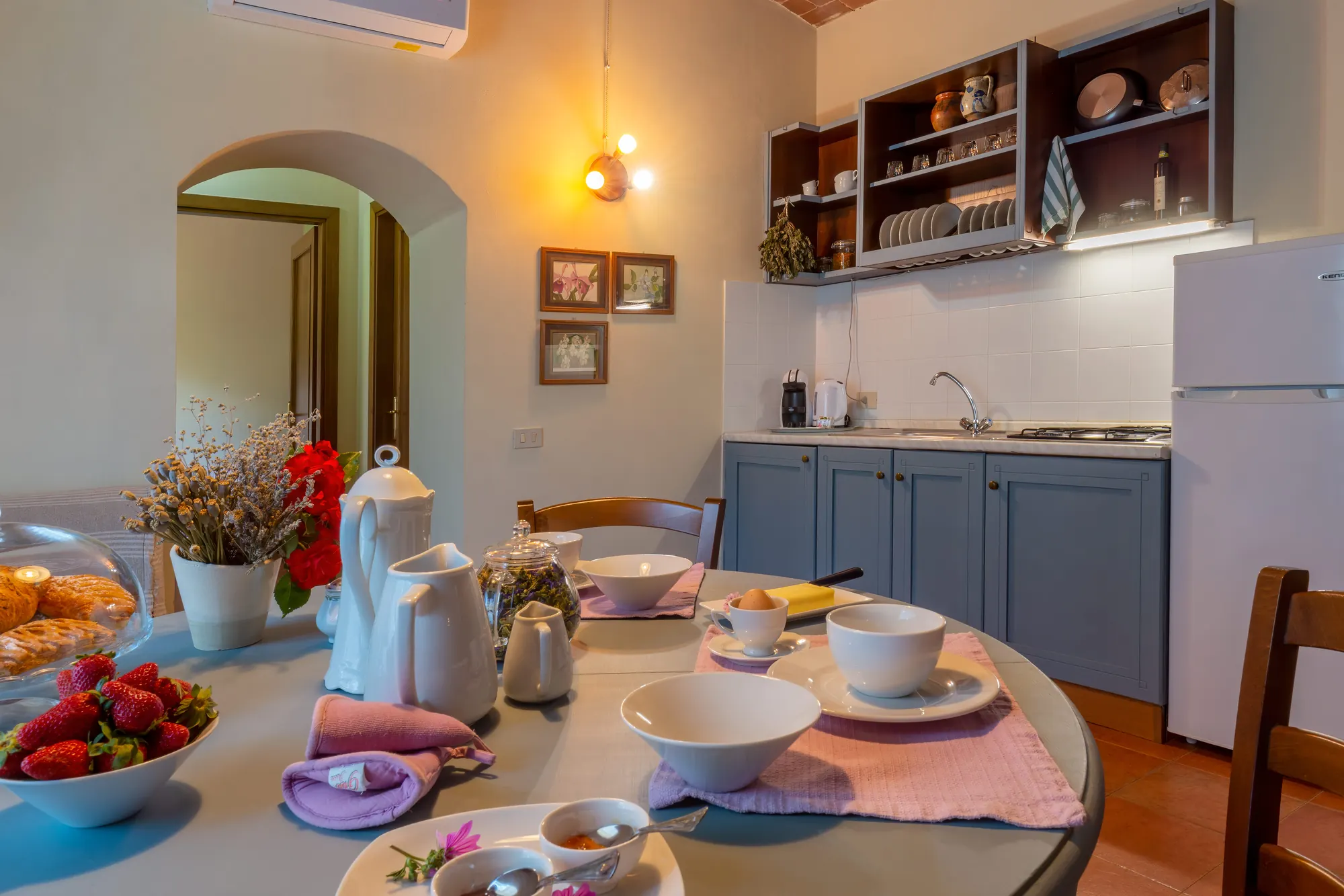 Tavola apparecchiata per la colazione in una cucina accogliente, con frutta, tazze e brioche