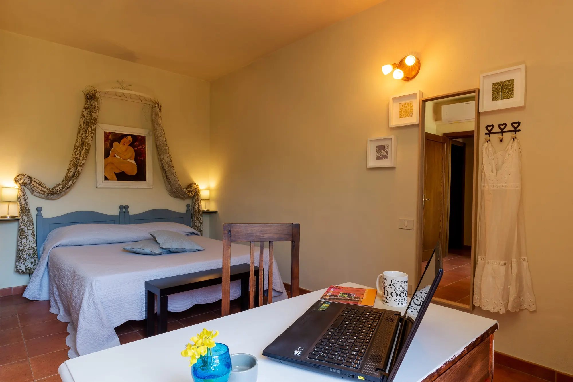 Camera da letto con letto matrimoniale, scrivania con laptop e decorazioni alle pareti