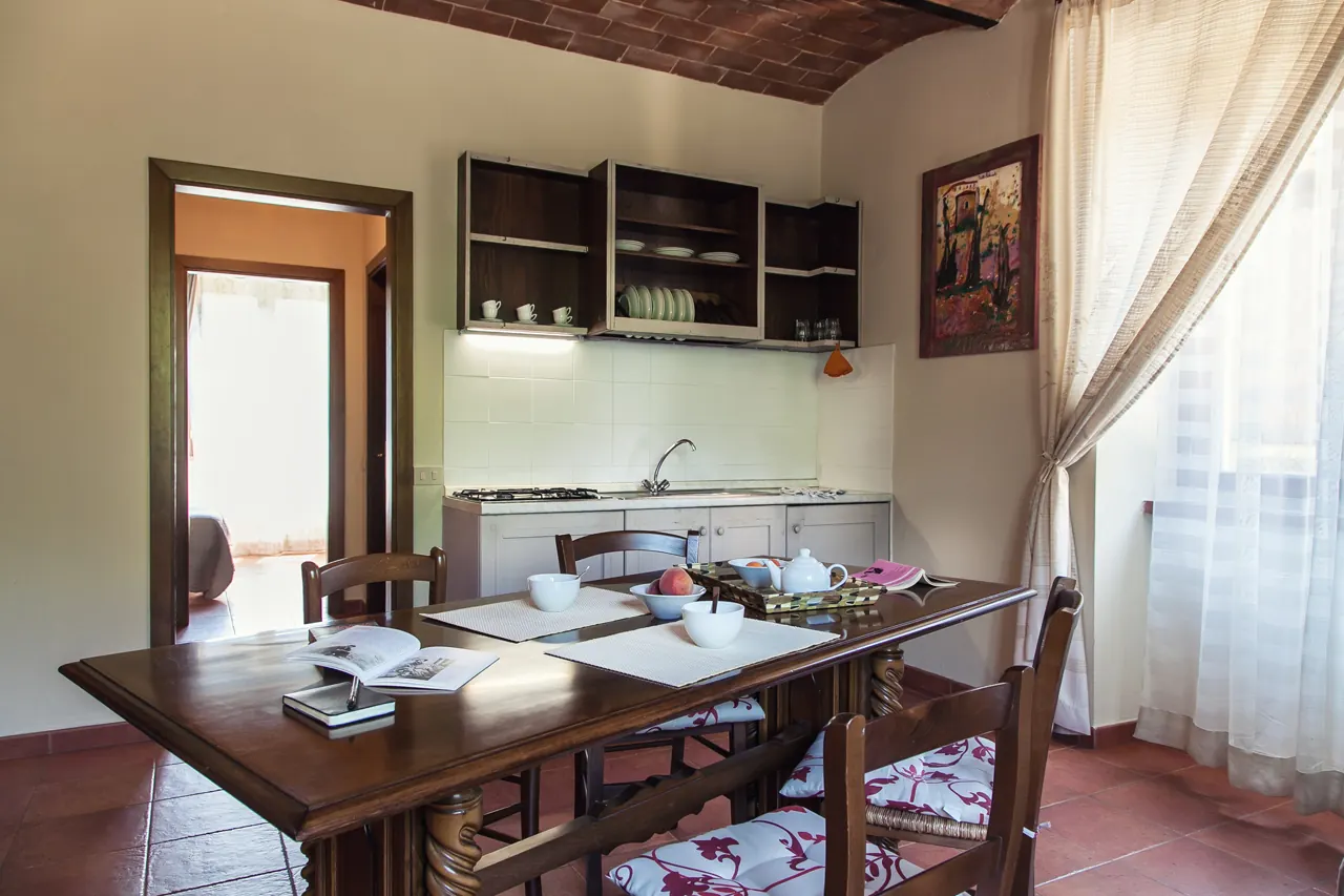 Cucina-sala da pranzo con tavolo apparecchiato, finestre luminose e pensili aperti