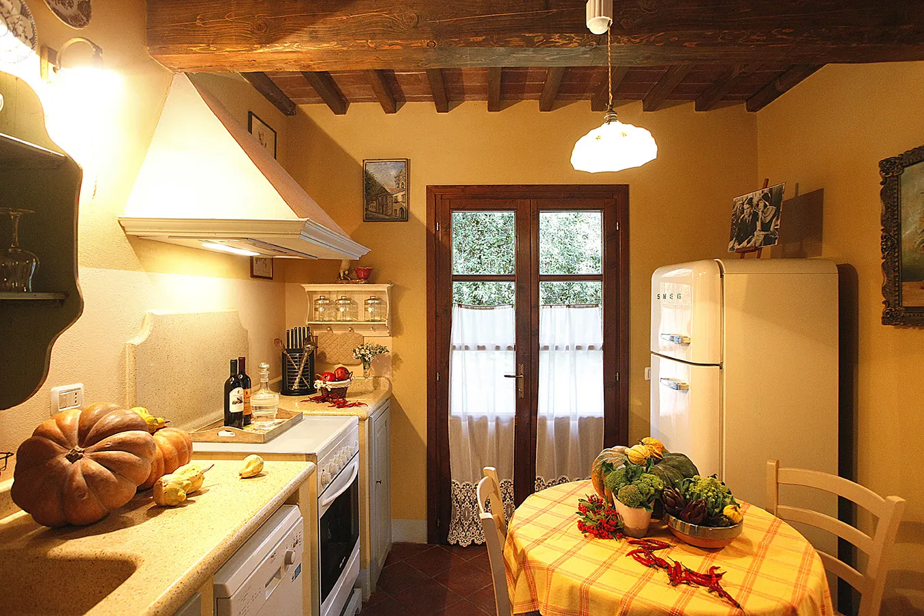 Cucina rustica con tavolo apparecchiato, frigorifero retrò e zucche decorative sul piano di lavoro