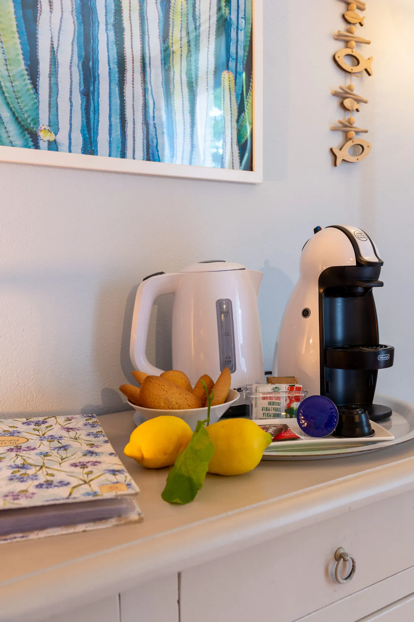 Angolo cucina con bollitore, macchina da caffè, limoni e biscotti su un vassoio