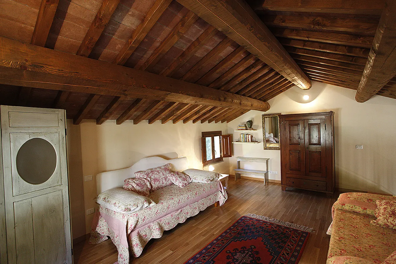 Camera da letto rustica con travi in legno a vista, letti singoli, armadio e finestra aperta
