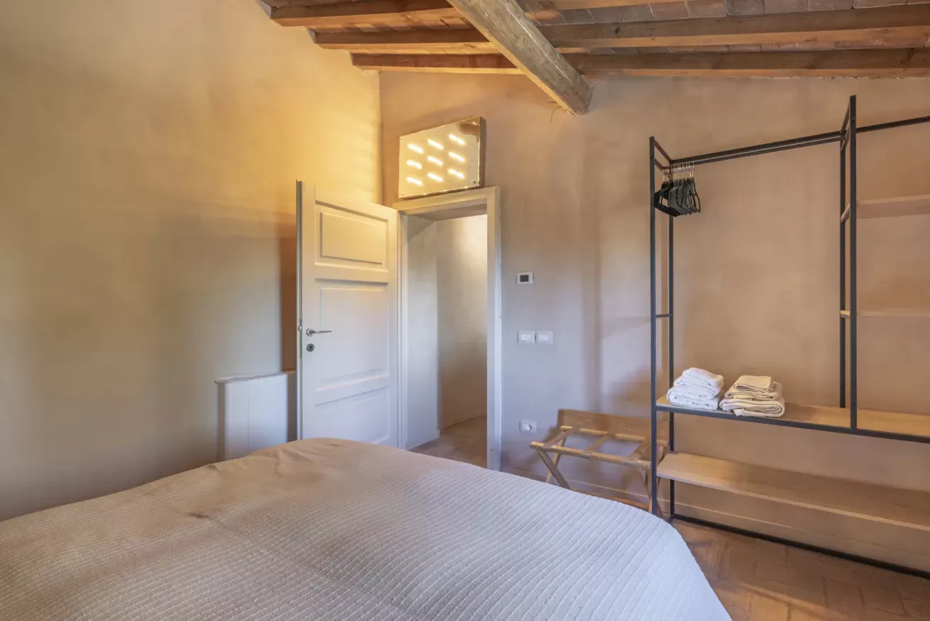Camera da letto con letto matrimoniale, armadio aperto e porta bianca aperta