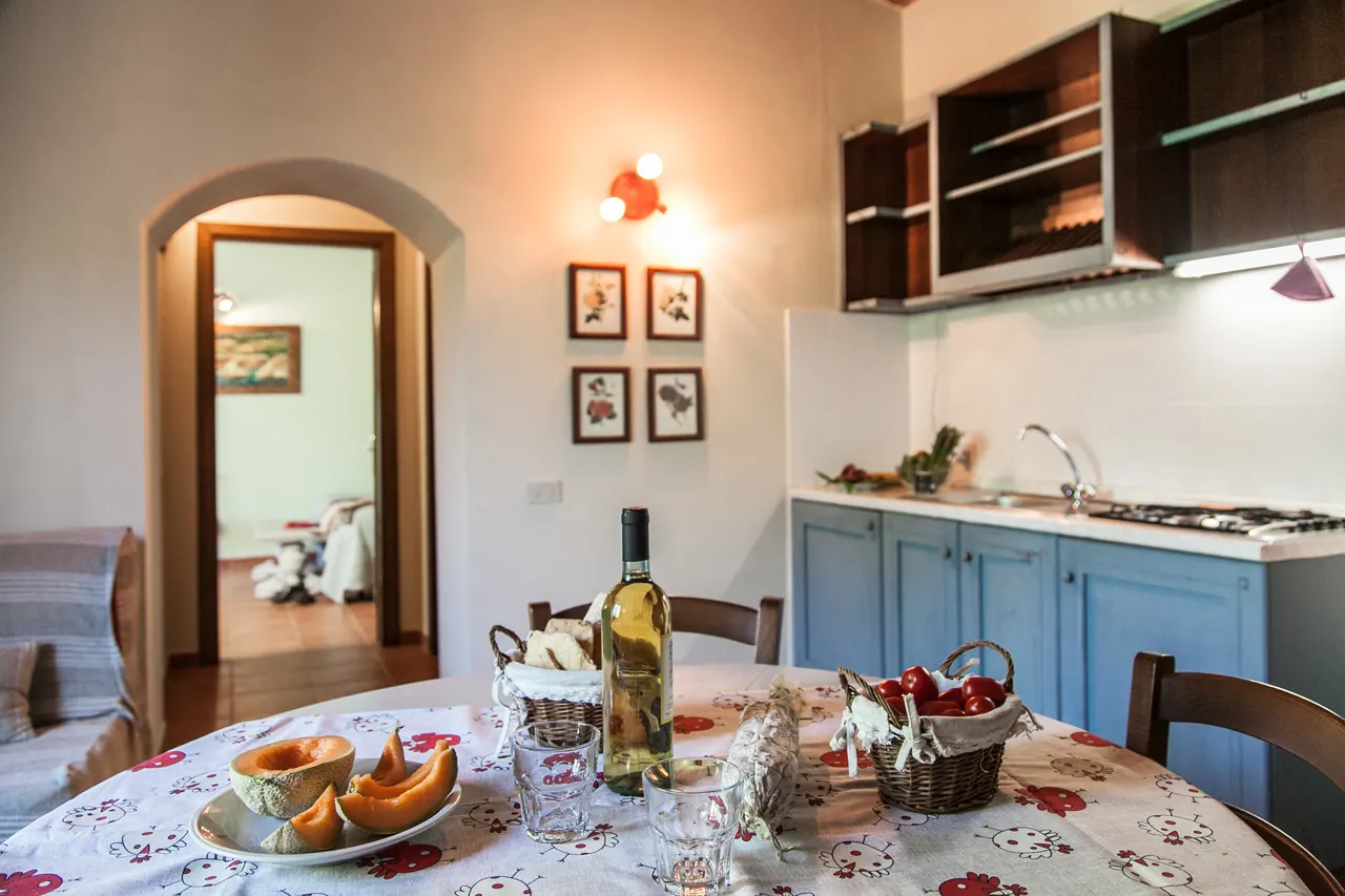 Cucina con tavolo apparecchiato, frutta, pane e bottiglia di vino