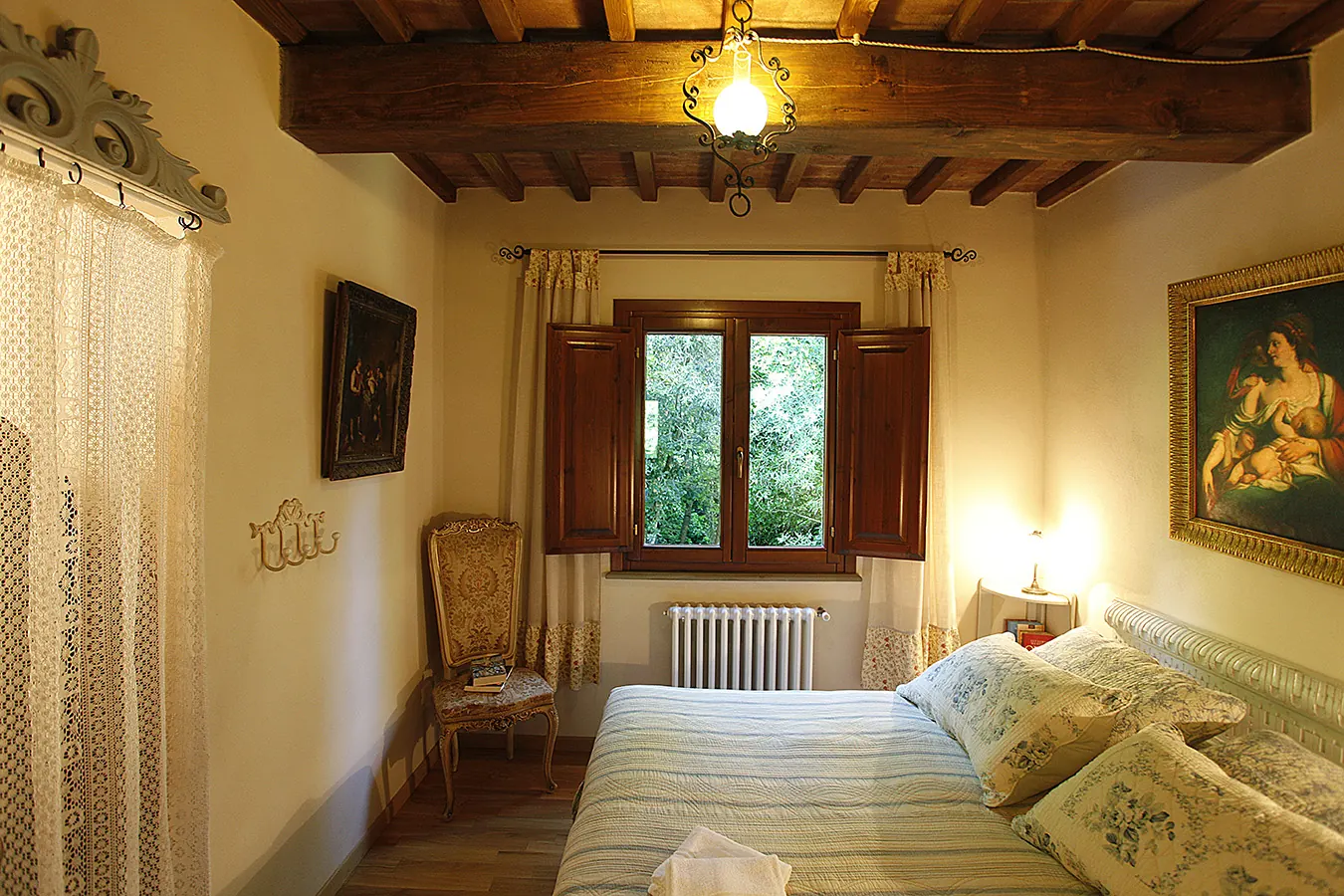 Camera da letto accogliente in stile rustico con letto matrimoniale, finestra aperta e travi in legno a vista