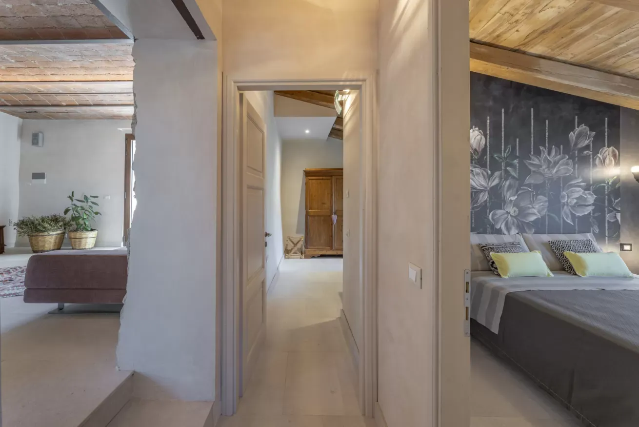 Corridoio interno che collega due camere da letto, con arredi moderni e soffitto in legno