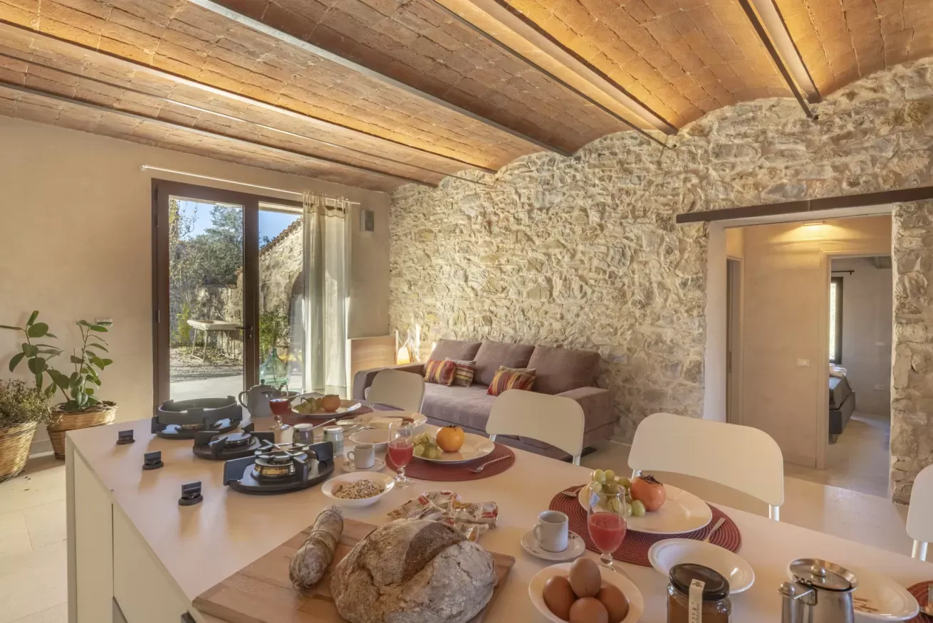 Interno rustico con tavolo apparecchiato per la colazione e parete in pietra a vista