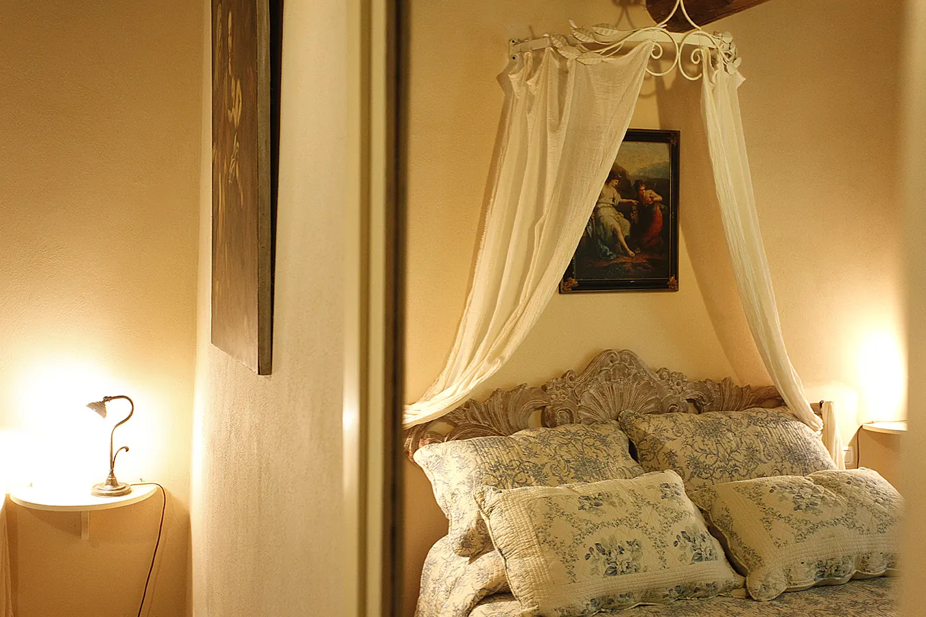 Camera da letto elegante con letto a baldacchino, cuscini floreali e lampade accese ai lati