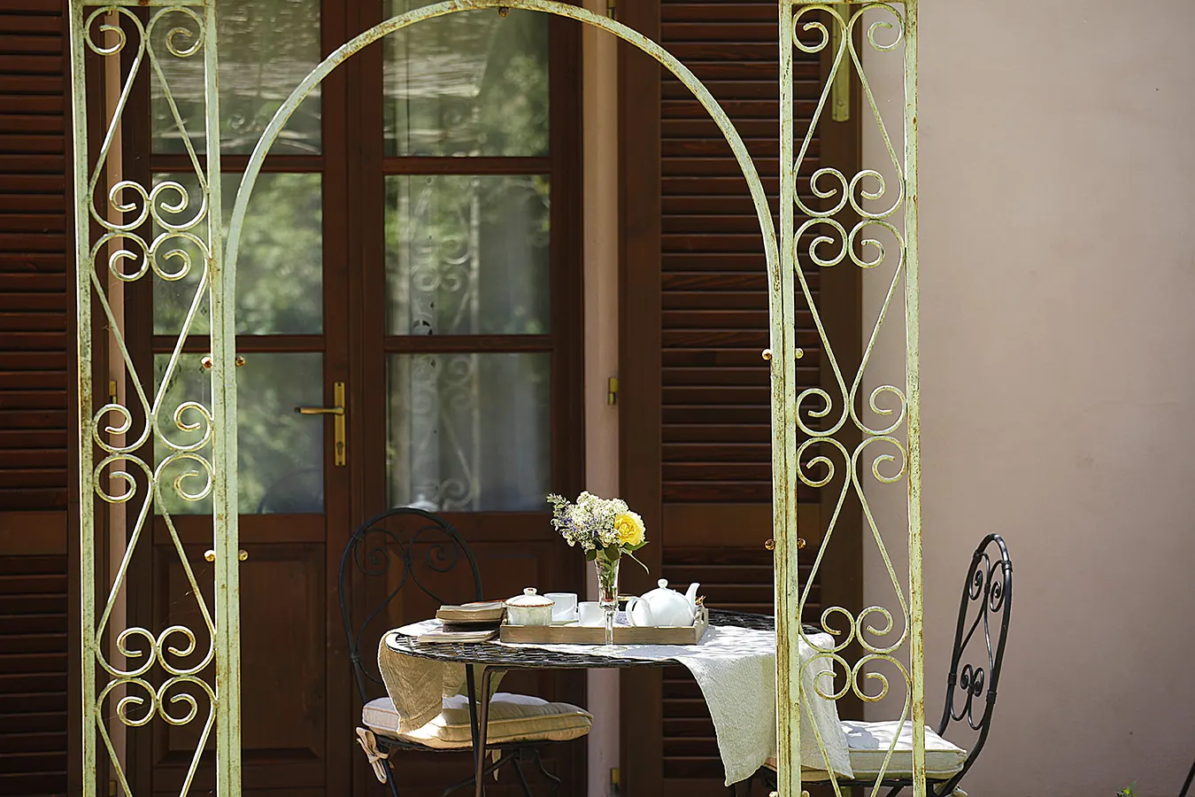 Tavolino apparecchiato con fiori su un patio davanti a una porta finestrata