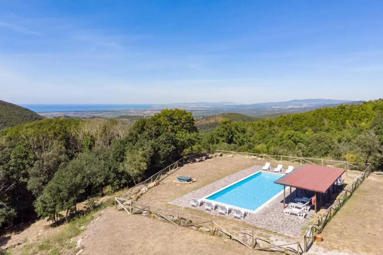 Hilltop pool with lounge chairs overlooking a wooded valley and distant coastline