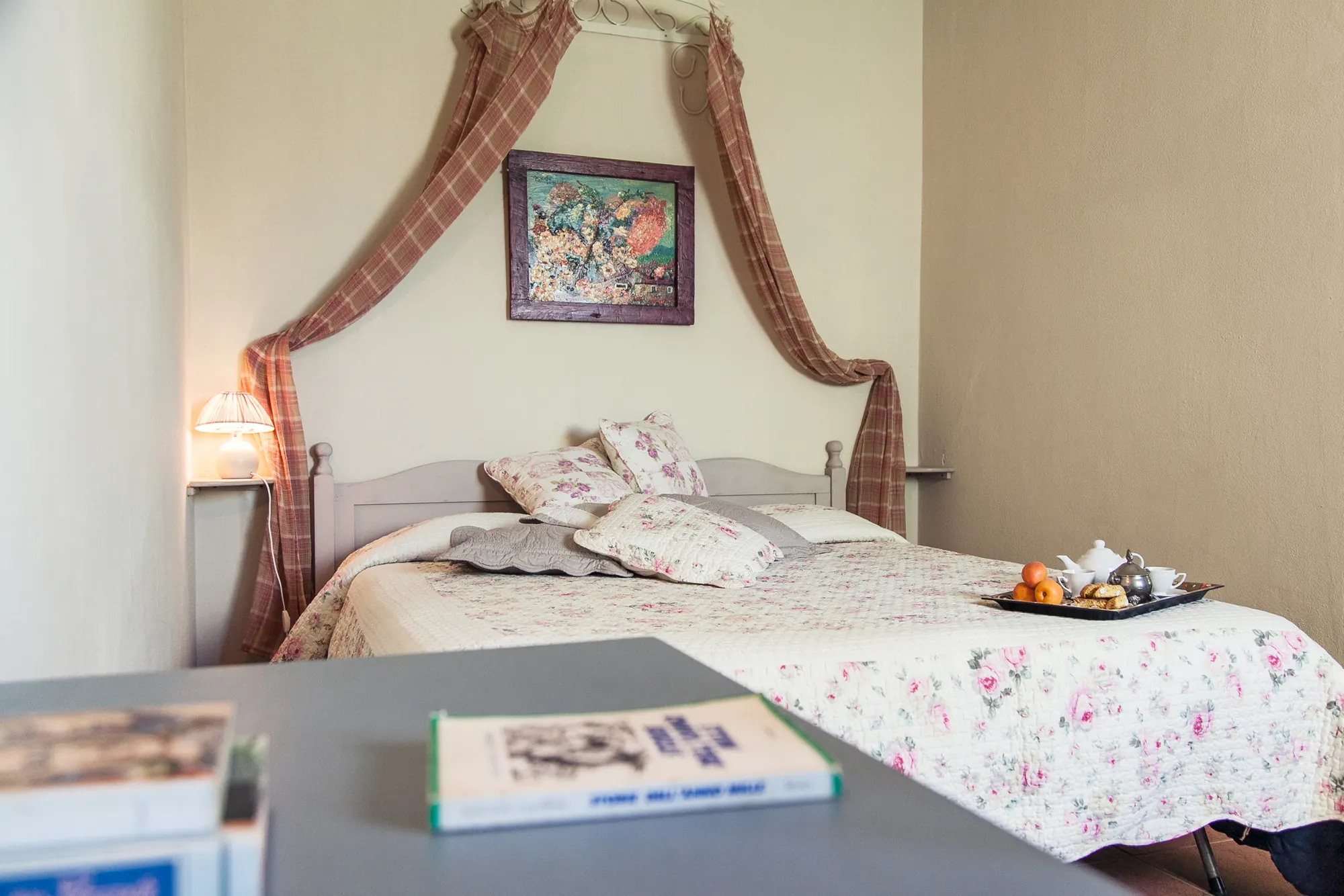Camera da letto accogliente con letto rifatto, lampada accesa e vassoio con colazione sul letto