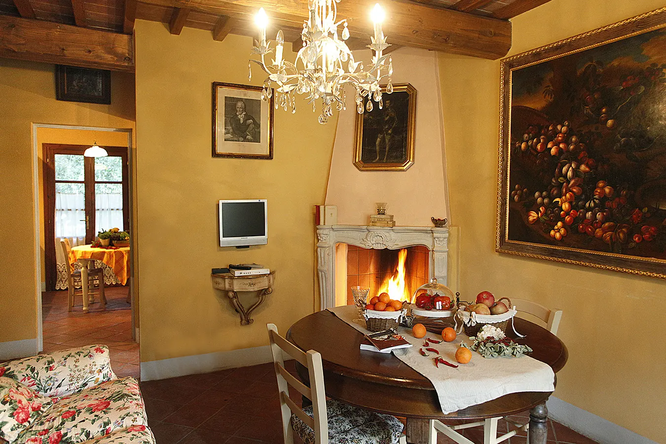Salotto elegante con camino acceso, tavolo apparecchiato e lampadario in cristallo