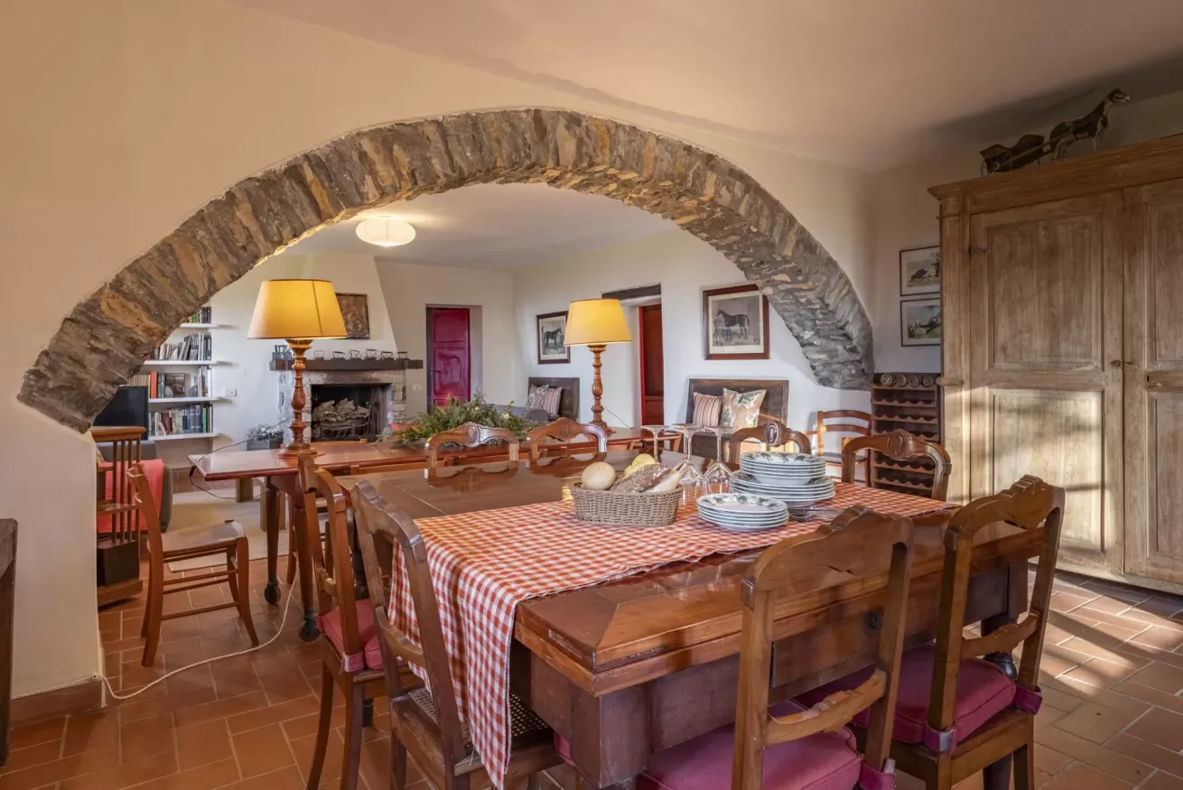 Rustic dining room with a stone arch, wooden table set for a meal, and a large cabinet
