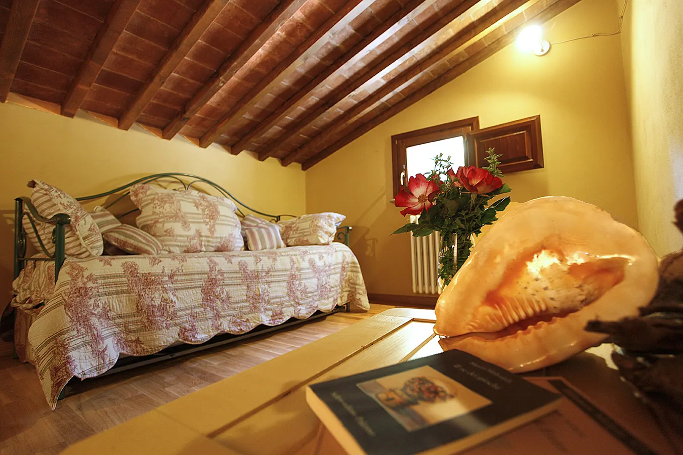 Camera da letto rustica con letto singolo, travi in legno a vista e conchiglia decorativa in primo piano