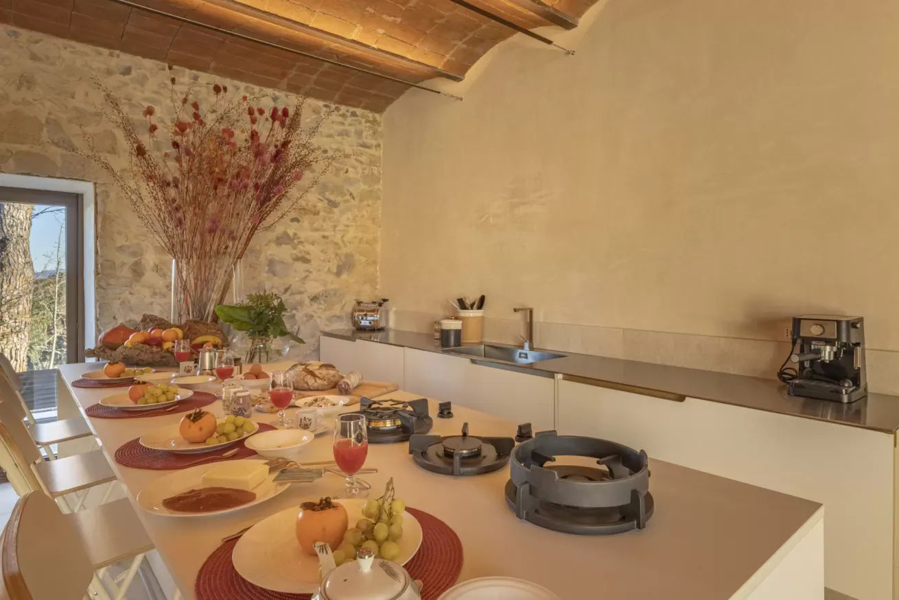 Cucina rustica con tavolo apparecchiato per la colazione e piano cottura sull’isola